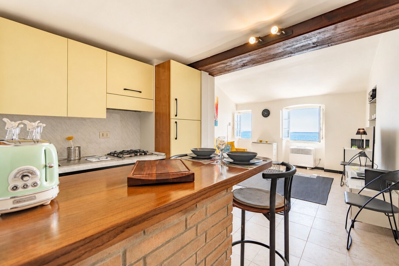 A kitchen with a wooden island, a gas stove, and a vintage toaster. There is a dining area with a table and chairs.