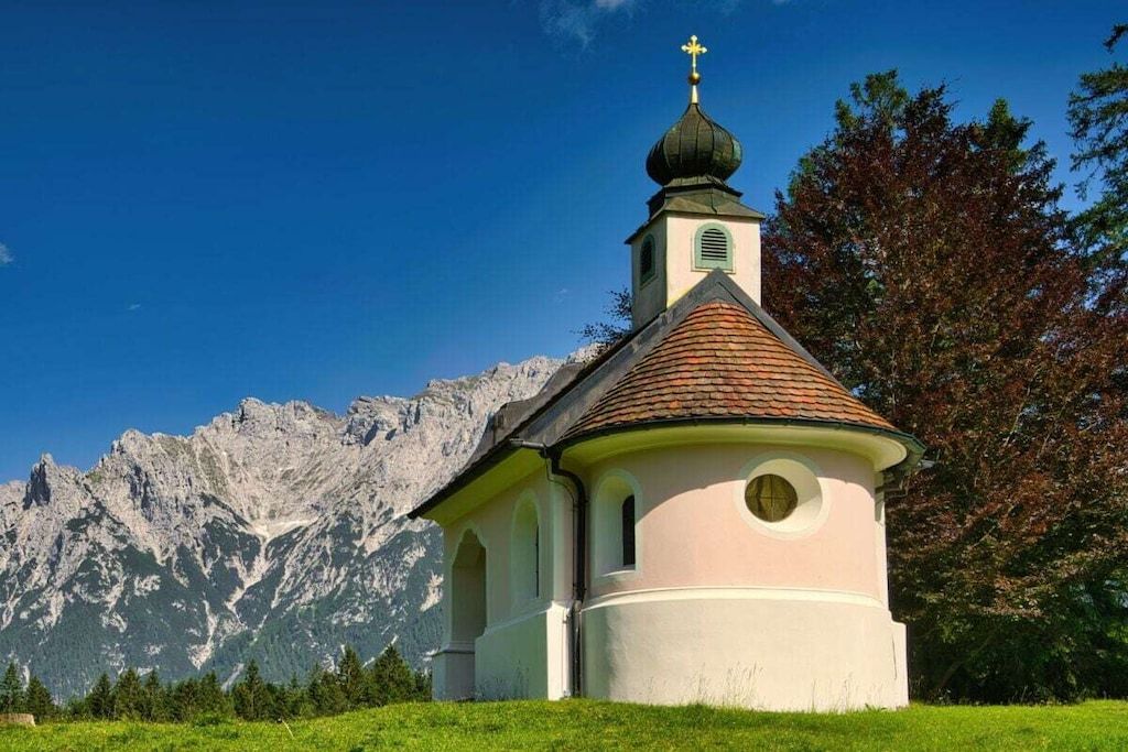 En lille kirke med et kirketårn og et bjerg i baggrunden.
