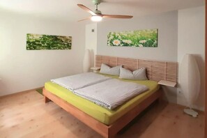 A bedroom with a bed, a ceiling fan, and two wall-mounted paintings. - Holiday apartment with 4 bedrooms (Mittenwald)