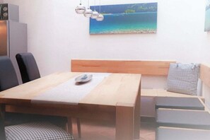 A dining area with a wooden table, chairs, and a bench. There is a painting on the wall and a ceiling light fixture. - Holiday apartment with 4 bedrooms (Mittenwald)