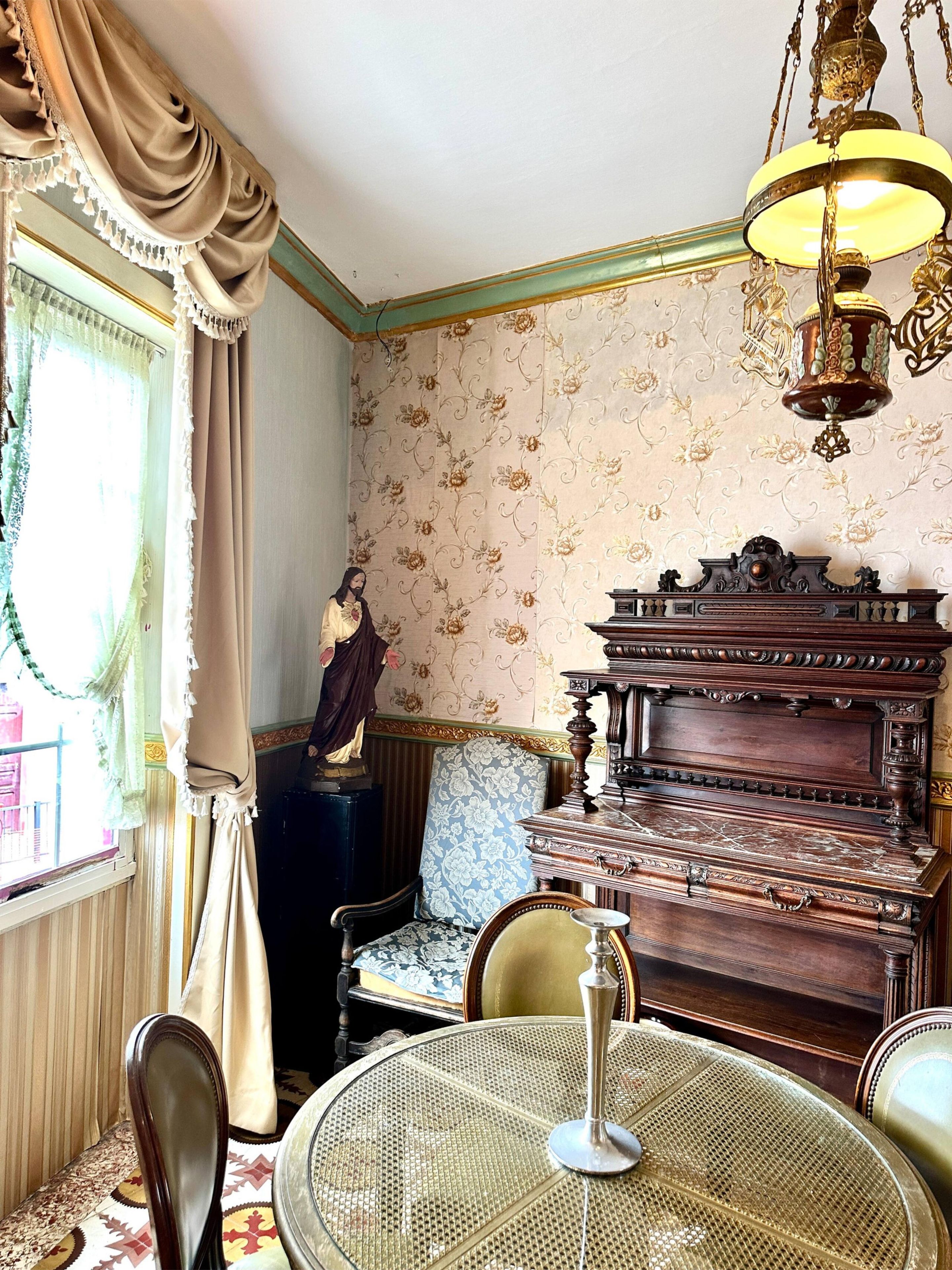 A room with a vintage piano, a table with a glass top, and a decorative lamp.