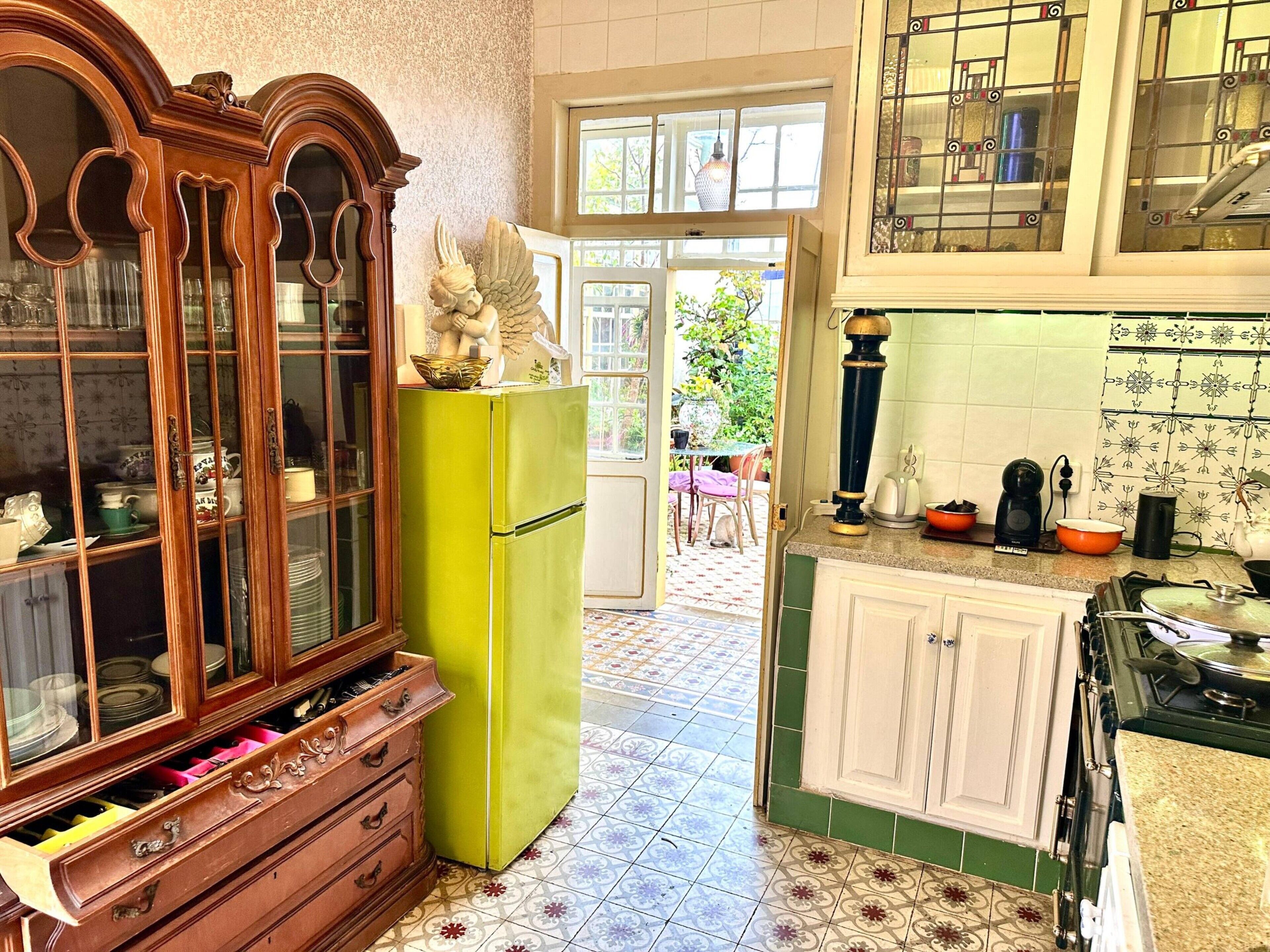 Eine Küche mit einem Holzkasten, einem grünen Kühlschrank und einem gefliesten Boden.