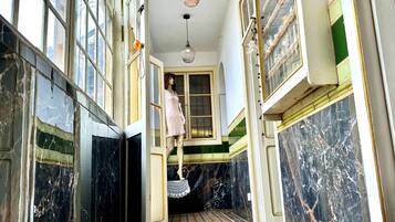 A corridor with a tiled floor, a mannequin, and a staircase.