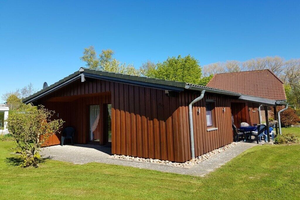 A wooden building with a covered porch and a gravel driveway.