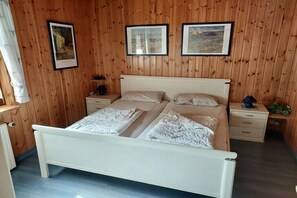 Een slaapkamer met een bed, twee nachtkastjes, een wandplank en een nachtkastje.