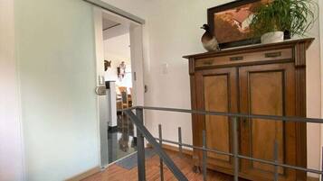 Een gang met een houten kast, een metalen balustrade en een deur naar een andere kamer.