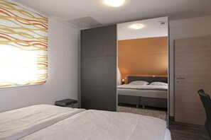 A hotel room with a bed, a wardrobe, a small table, and a window with curtains. - Holiday home with 3 bedrooms (Göhren Lebbin)