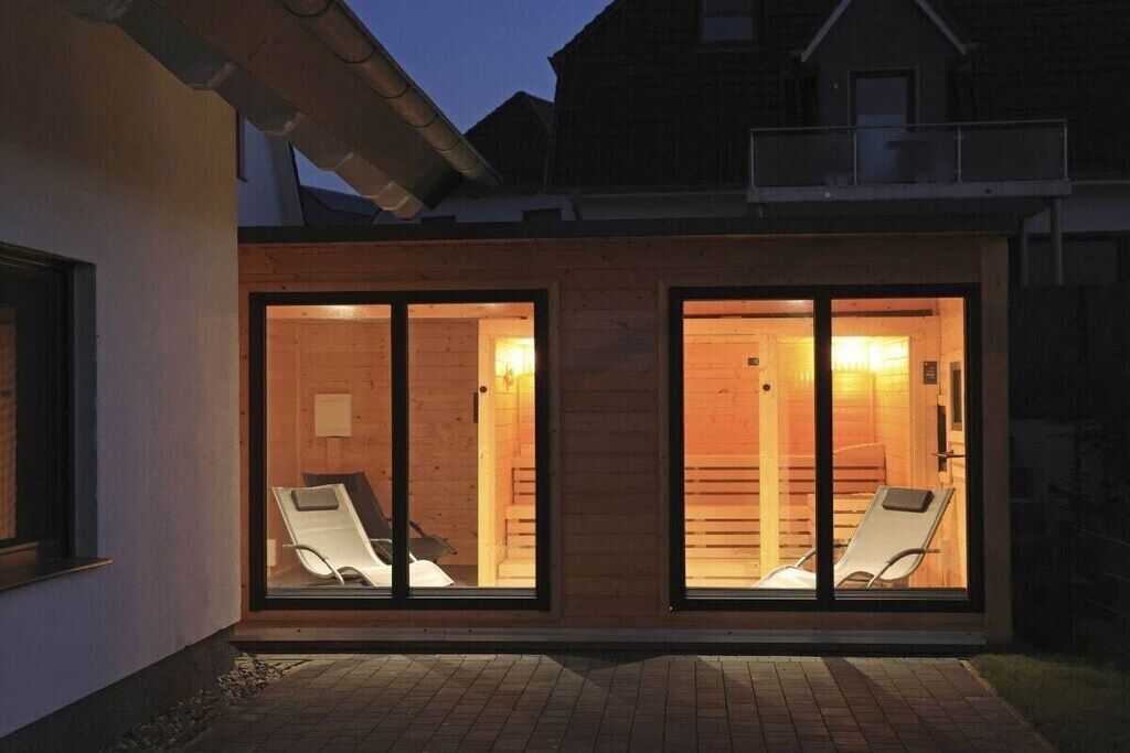 Un edifici modern amb dues portes de vidre grans que donen a una sala amb dos seients còmodes blancs.