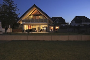 A two-story house with a balcony, a fenced yard, and a clear sky. - Holiday home with 3 bedrooms (Göhren Lebbin)