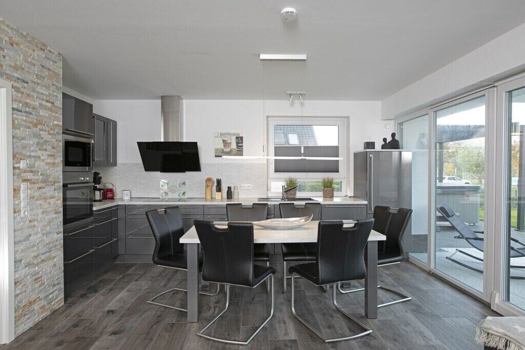 Een moderne keuken met een eethoek, grote ramen en uitzicht op de omgeving.