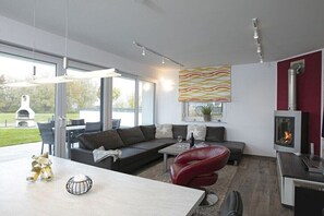 A modern living room with a sectional sofa, a red chair, a coffee table, and a fireplace. - Holiday home with 3 bedrooms (Göhren Lebbin)