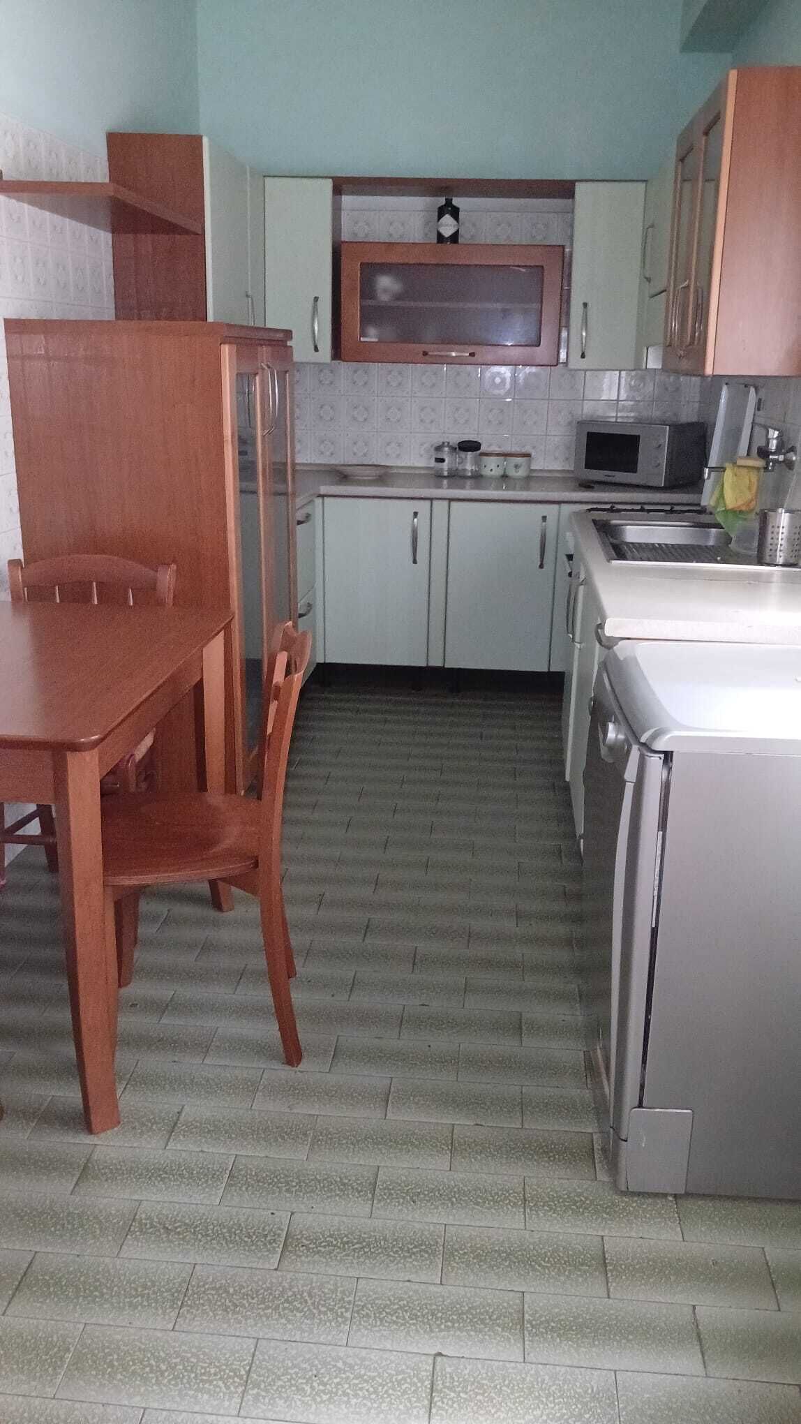 A kitchen with a wooden dining table, cabinets, a microwave, and a stove.