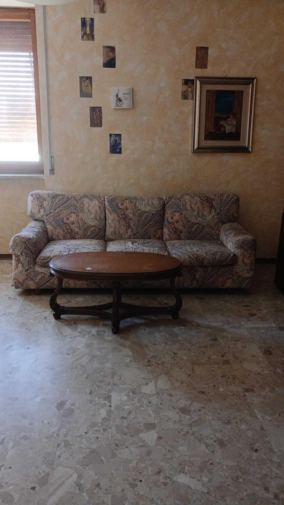 A living room with a patterned sofa, a wooden coffee table, and a framed picture on the wall.