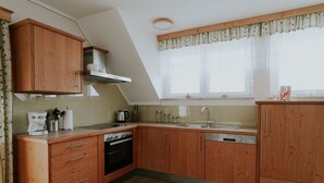 Cuina moderna amb armaris de fusta, forn integrat i finestra amb cortines.