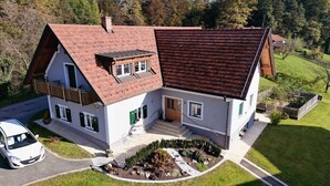 Una casa de dues plantes amb teulada inclinada, un porxo i un jardí ben condicionat.