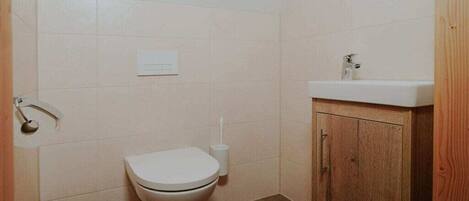 A small bathroom with a toilet, a sink, and a cabinet.