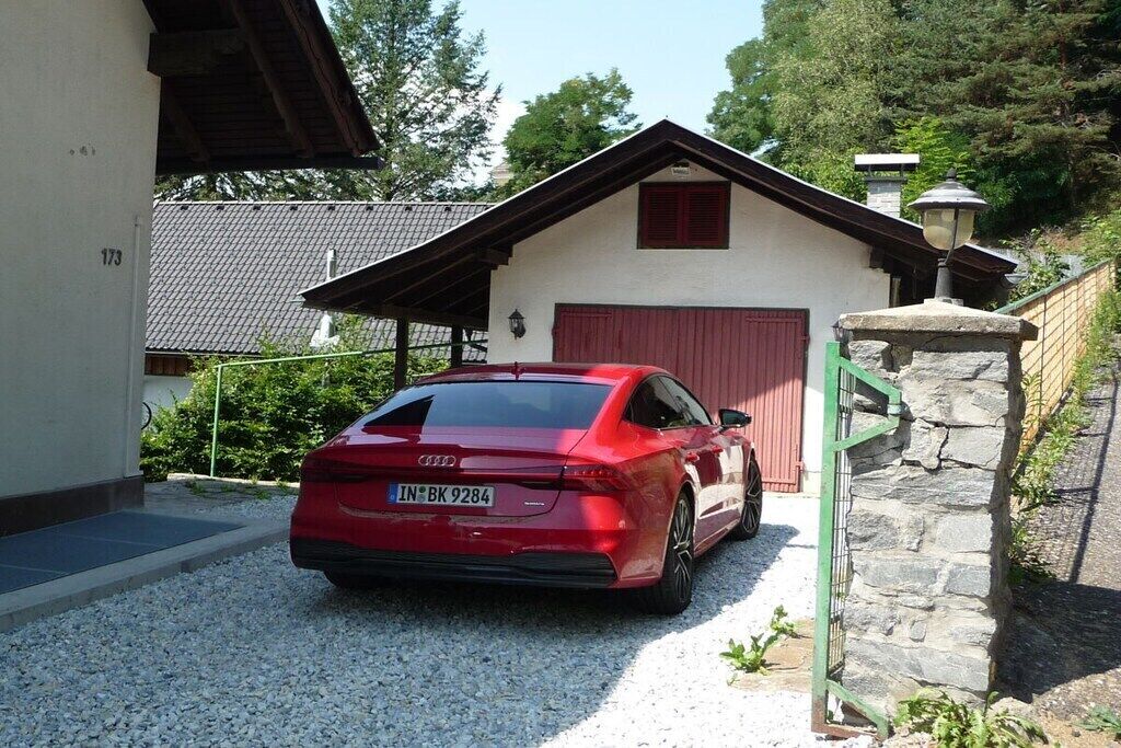 Un coche rojo estacionado frente a un edificio con una pared de piedra y una puerta roja.