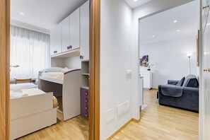 A modern hotel room with a bed, a desk, a sofa, and a wardrobe. - Vatican Flat 2 Bedrooms 2 Ensuite Baths (Roma)