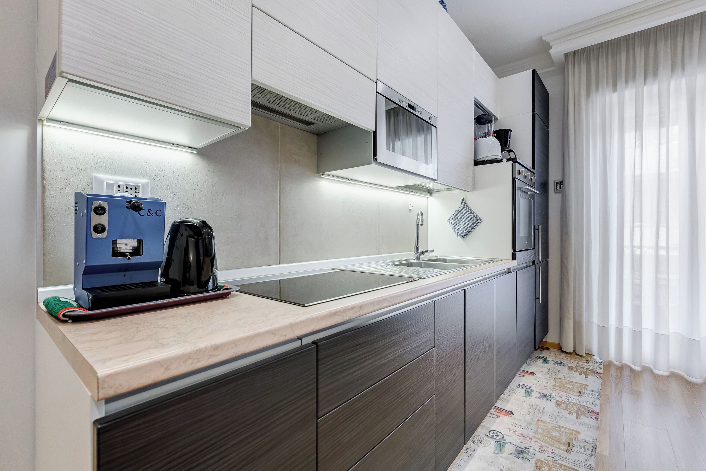A modern kitchen with a built-in stove, a microwave, and a coffee machine.