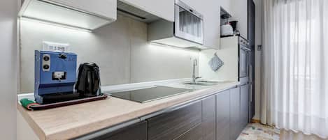A modern kitchen with a built-in stove, a microwave, and a coffee machine.