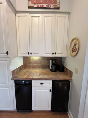 A kitchen with white cabinets, a coffee maker, and a dishwasher. - 3-Bedroom House At Safe Harbor Aqua With Lake Vew, Iuka MS (Iuka)