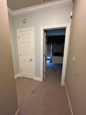 A hallway with a closed door on the left and an open door leading to a room with a bed and a window. - 3-Bedroom House At Safe Harbor Aqua With Lake Vew, Iuka MS (Iuka)