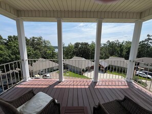A covered outdoor deck with wicker furniture and a view of neighboring houses. - 3-Bedroom House At Safe Harbor Aqua With Lake Vew, Iuka MS (Iuka)