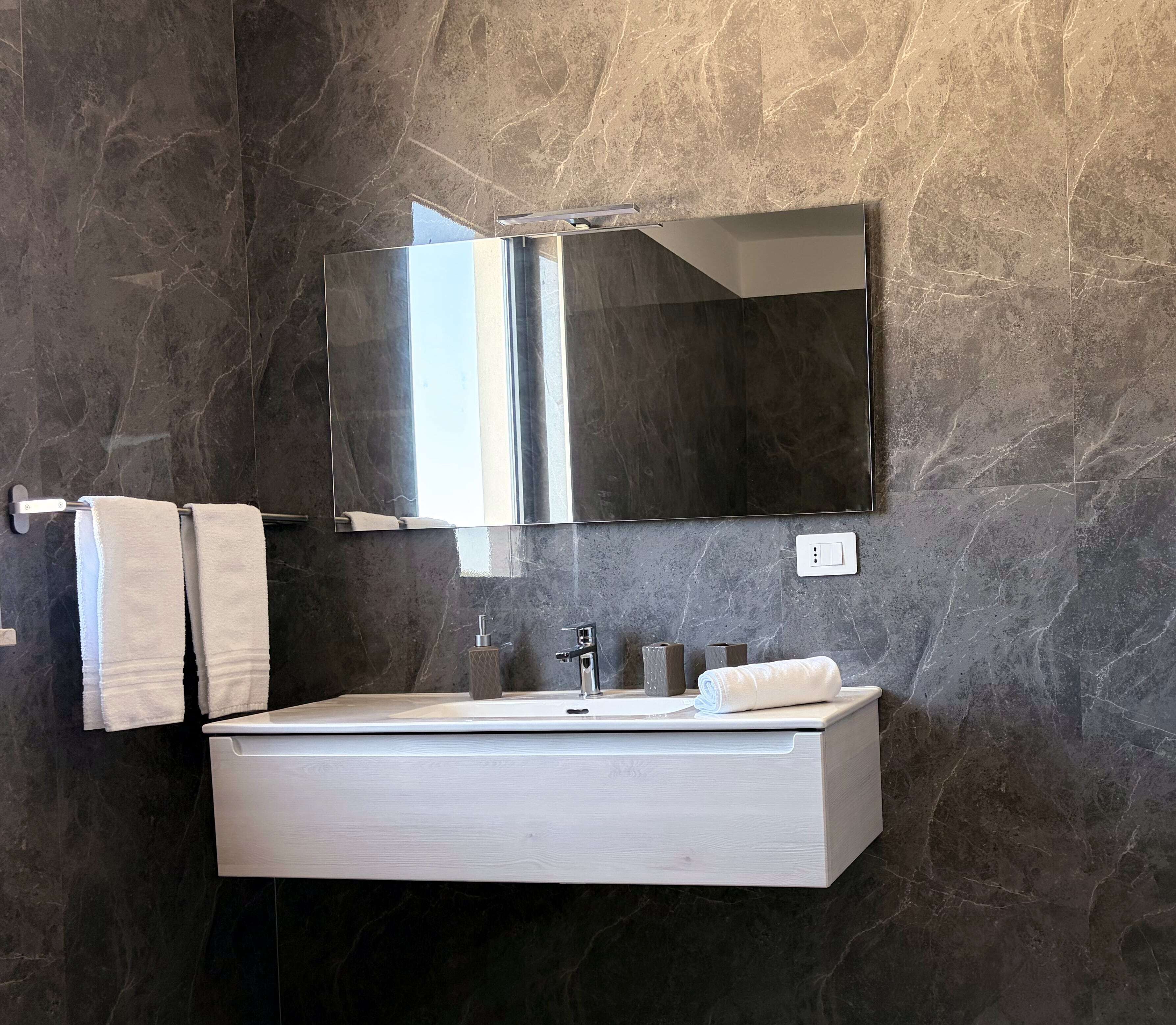 Une salle de bain avec un meuble-lavabo rectangulaire, un miroir et un porte-serviettes.