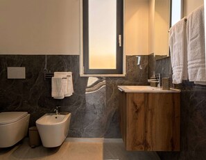 A modern bathroom with a bidet, vanity, and a large mirror. - Tenuta San Tommaso Mare (Basilicata)