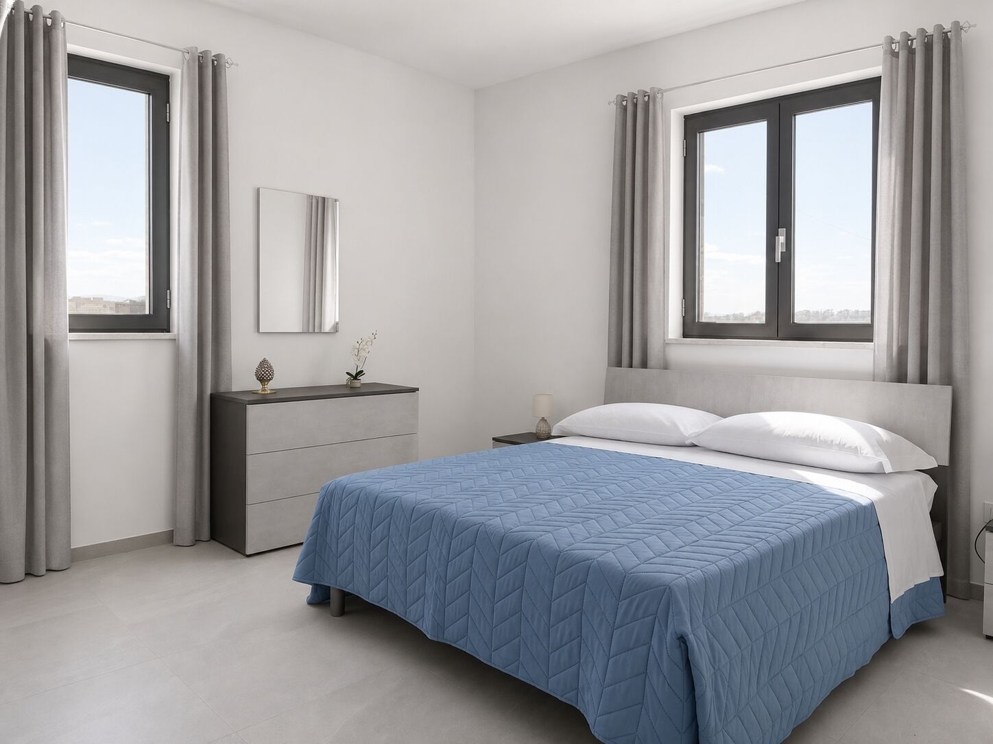 Un dormitorio con cama, cómoda, espejo y dos ventanas con cortinas.