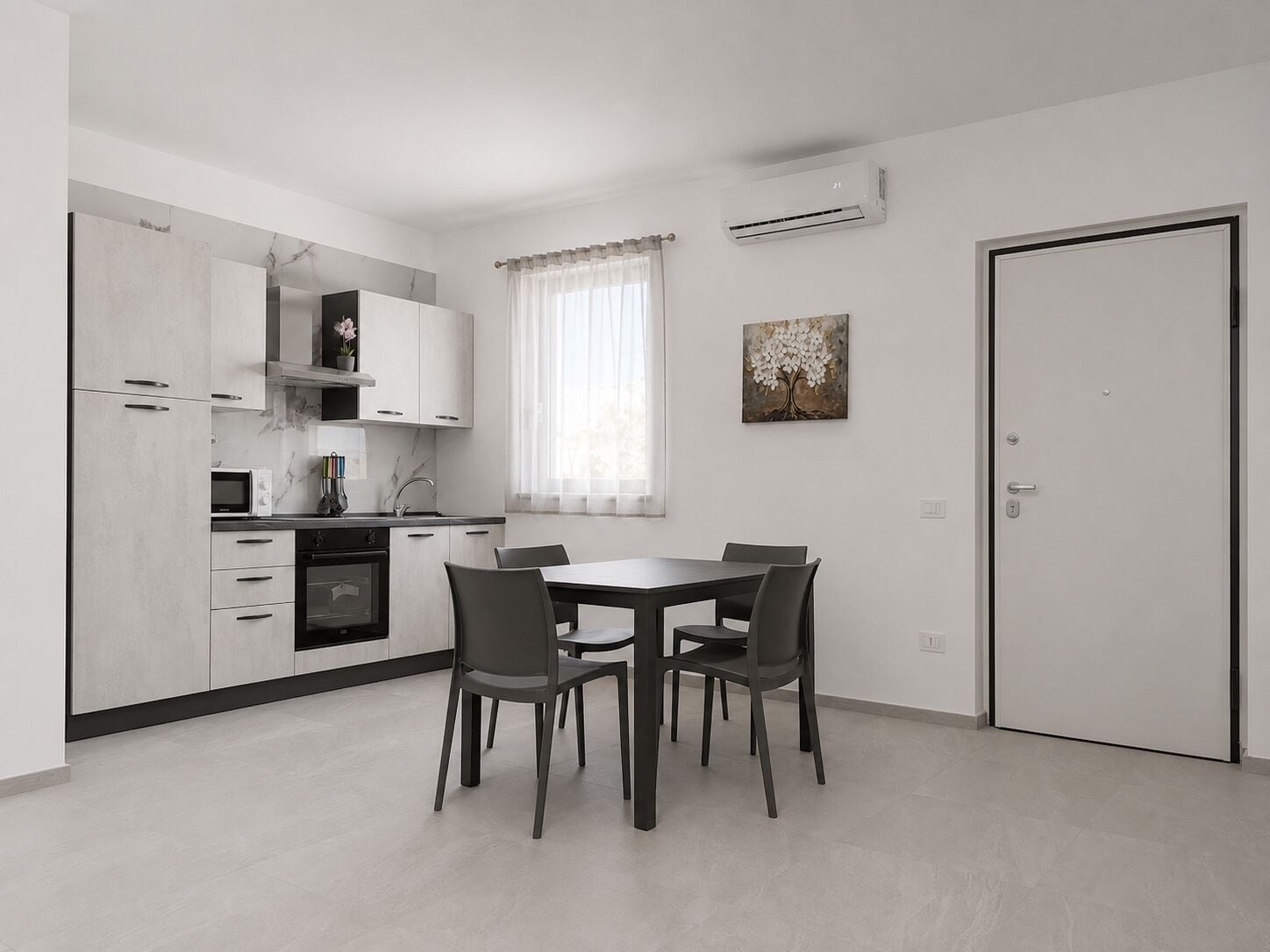 A modern kitchen with white cabinets, a dining table with four chairs, and an air conditioning unit on the wall.