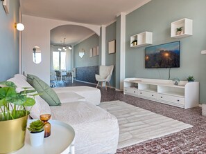 Een moderne woonkamer met een hoekbank, een eethoek en een wandtelevisie.