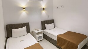 A hotel room with two single beds, a small bedside table with a phone, and a wall-mounted air conditioner. - Marine Point Pansiyon (Antalya)