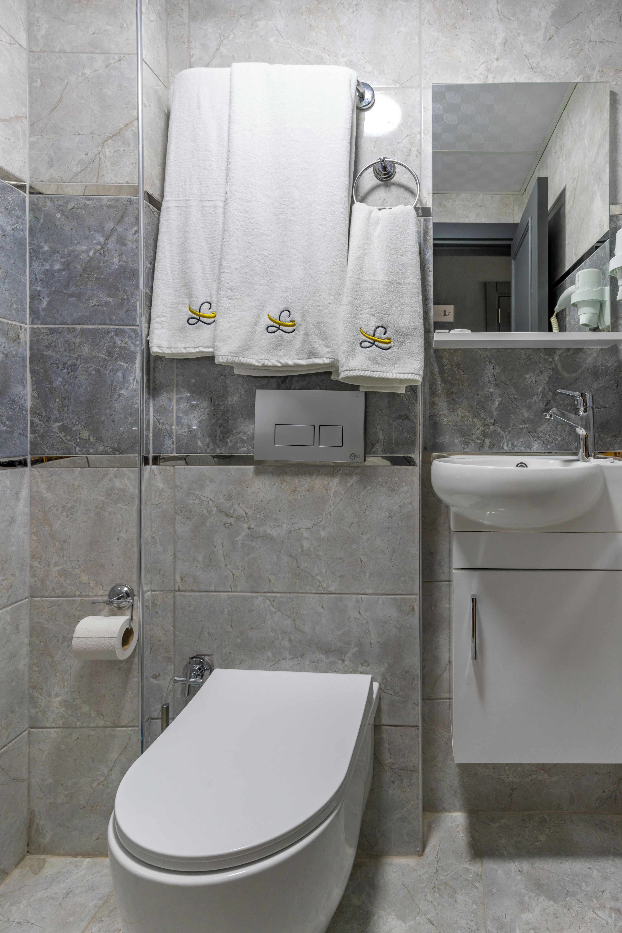 Un baño moderno con inodoro, lavamanos y perchero para toallas.