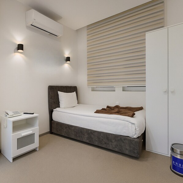 Un dormitorio con cama, mesita de noche, lámpara y aire acondicionado.