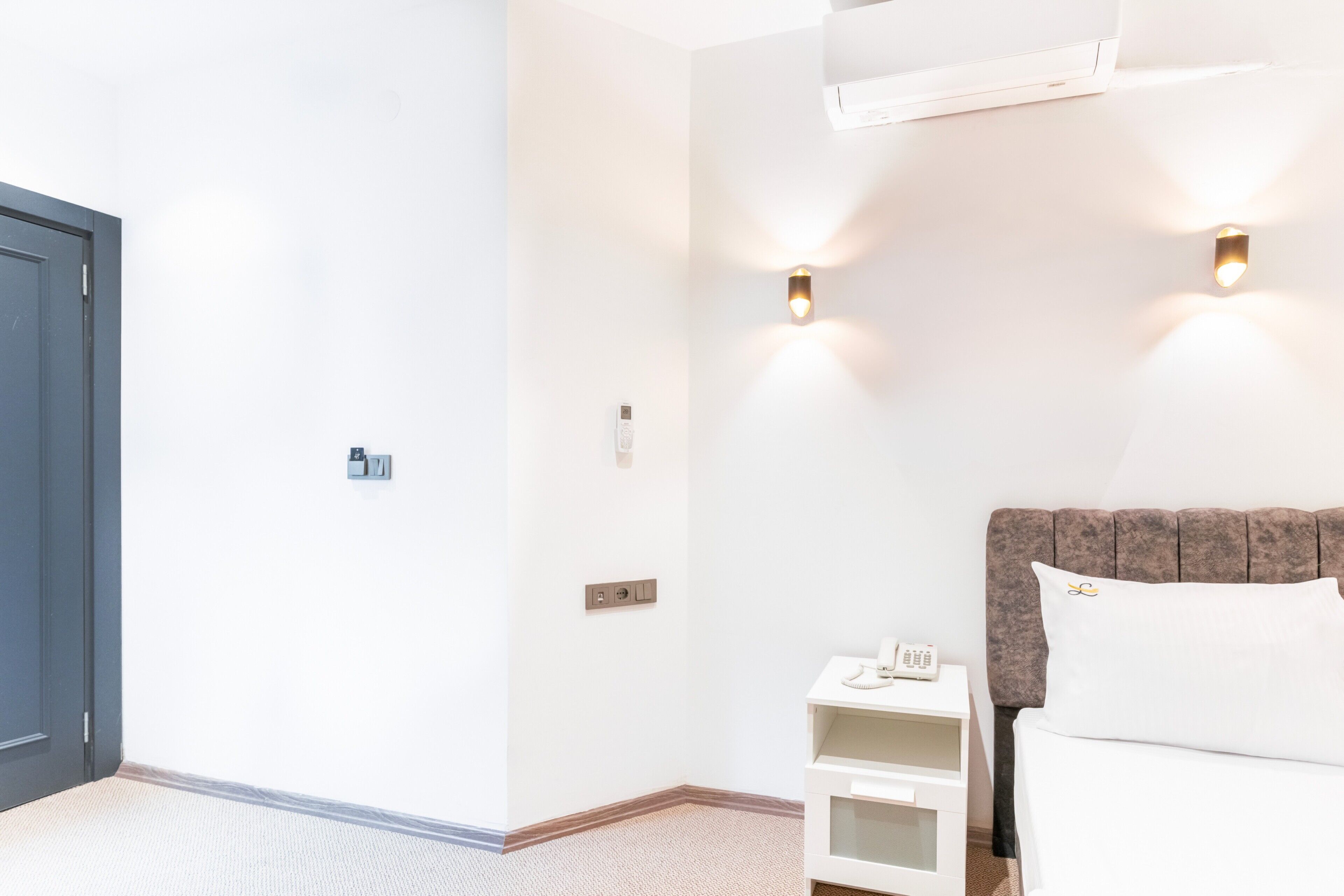 Une chambre d’hôtel équipée d’un lit, d’une table de chevet et d’un climatiseur fixé au mur.