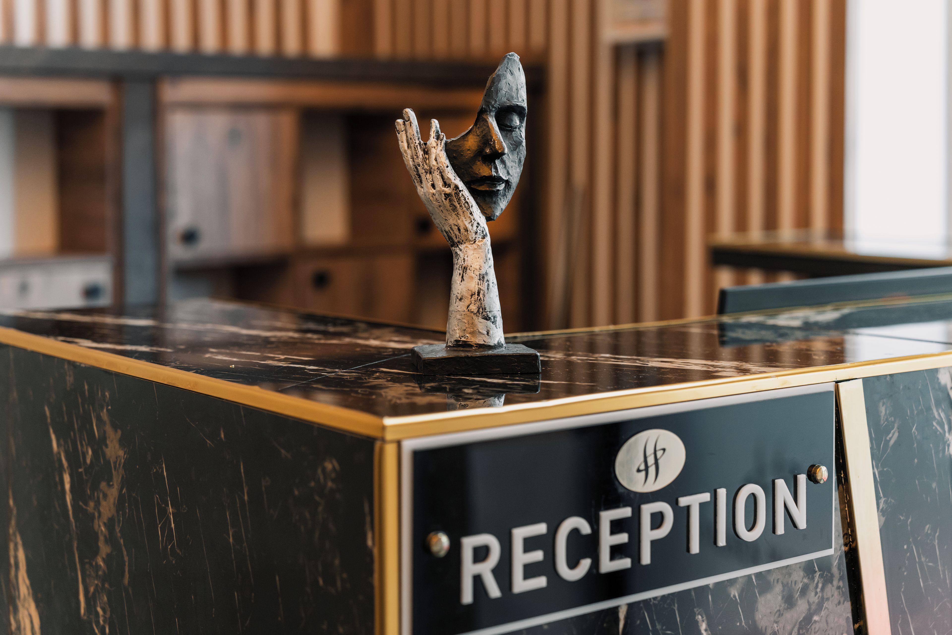 Un comptoir d’accueil avec une pancarte indiquant « RÉCEPTION » et une sculpture représentant une main.