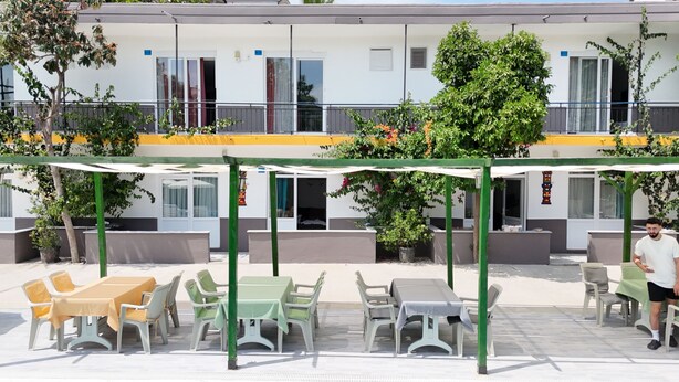 Ein Hotel mit Außenbereich, einer überdachten Terrasse und einem Gebäude mit mehreren Fenstern und Balkonen.