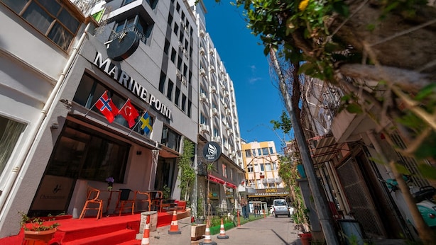 A building with a sign reading "MARINE POINT" and flags of Denmark, Sweden, and Finland. - Marine Point Pansiyon (Antalya)