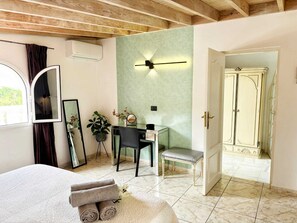 Une chambre à coucher comprenant un lit, un bureau, une chaise, un miroir, une plante en pot et une armoire.