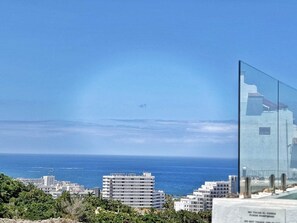 A coastal cityscape with a clear view of the sea, modern buildings, and a glass structure reflecting the sky. - Panoramic Villa Siam with a private swimming pool (Costa Adeje)
