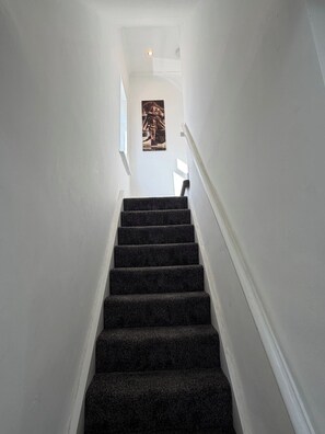 A staircase with carpeted steps leading to a landing. - 3 Bedroom House Sleeps 6 -garden -private Parking (Feltham)