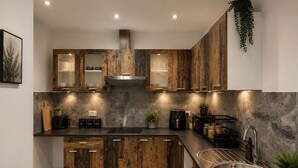 A modern kitchen with wooden cabinets, a stainless steel sink, and a built-in stove. - 3 Bedroom House Sleeps 6 -garden -private Parking (Feltham)