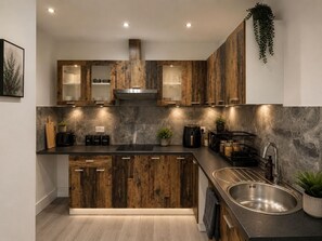 A modern kitchen with wooden cabinets, a stainless steel sink, and a built-in stove. - 3 Bedroom House Sleeps 6 -garden -private Parking (Feltham)