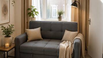 A modern living room with a grey sofa, a floor lamp, and a large window with curtains.