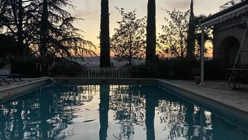 A swimming pool with a clear view of tall trees and a building in the background.