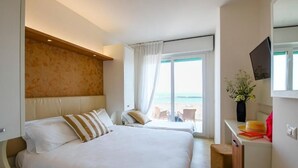 Une chambre d’hôtel avec un grand lit, un bureau doté d’une télévision à écran plat et une vue sur la plage.