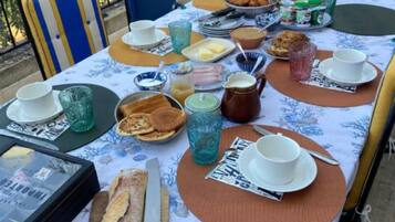 Een buitentafel met verschillende soorten eten, borden en bestek.