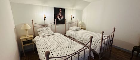 A bedroom with two single beds, a nightstand with a lamp, and a poster on the wall.