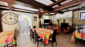 A dining area with a large table, chairs, a clock, and a television.